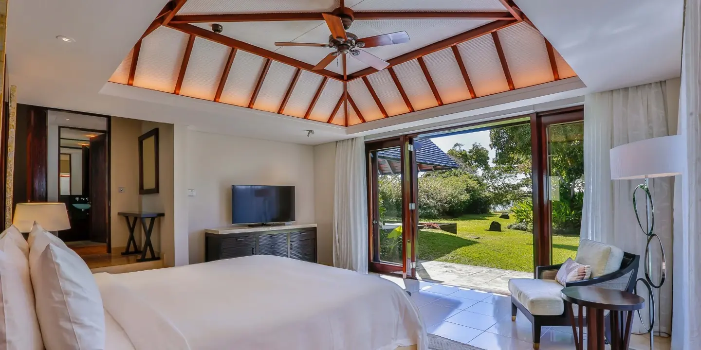 Primary suite of a Four Seasons villa at Anahita under a timber roof, opening onto the garden