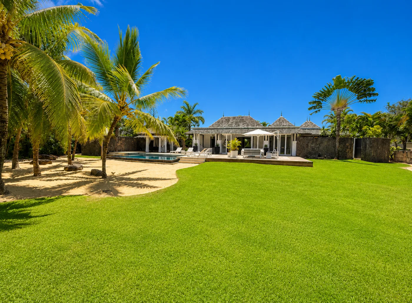 Luxury villa with large landscaped garden, pool and palm trees at Tamarina, Mauritius